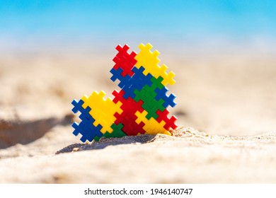 World autism awareness day background. Multicolored puzzle heart on the beach in sunny day. - Powered by Shutterstock