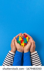 World Autism Awareness Day Concept. Adult And Child Hands Holding Puzzle Heart On Light Blue Background