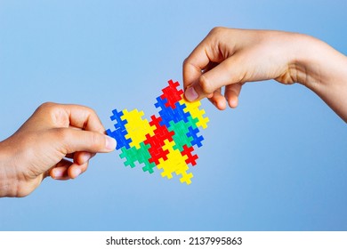 World autism awareness day concept. Children hands holding colorful puzzle heart on blue background - Powered by Shutterstock