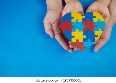 World Autism Awareness Day, Mental Health Care Concept With Puzzle Or Jigsaw Pattern On Heart With Child And Adult Hands