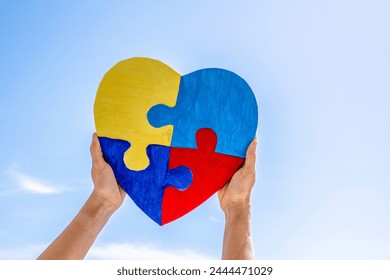 World autism awareness day, Autism spectrum disorder concept. Adult and child hands holding together colorful painted puzzle heart on blue sky background - Powered by Shutterstock