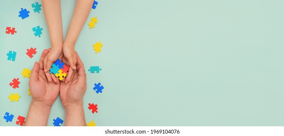 World autism awareness day. Understanding - love concept. The hands of an autistic father and child hold a colorful puzzle on blue background. ASD. Heart of puzzles.Copy space. Banner. Layout - Shutterstock ID 1969104076