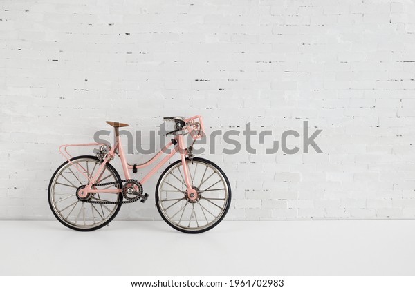 World bicycle day concept. Pink bicykle on white\
brick wall. 3 june.