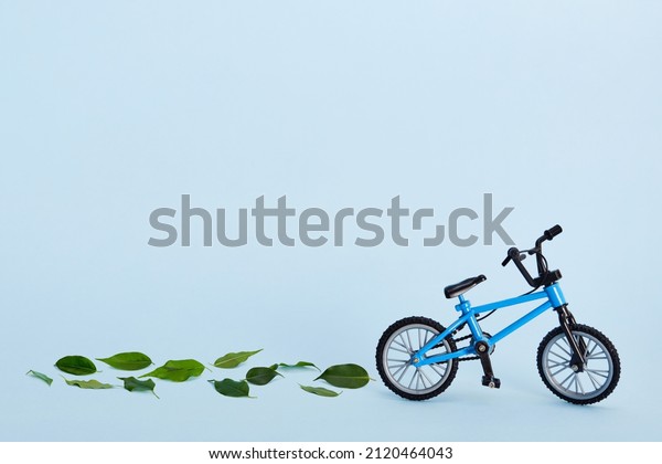 World\
bicycle day. Bicycle and tracks made from fresh green leaves on\
blue background. Sustainable and healthy\
concept