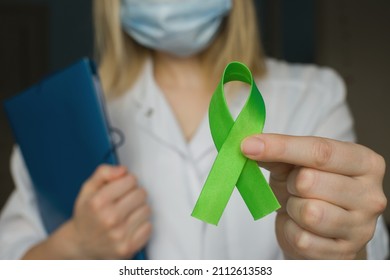 World Bipolar Day. Doctor In White Coat Holds Green Ribbon. Mental Health Awareness Day, Depression, Cerebral Palsy. World Kidney Day.