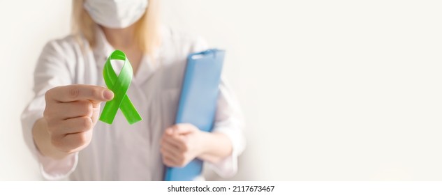 World bipolar day. Doctor in white coat holds green ribbon. Mental health awareness day, Depression, Cerebral palsy. World kidney day. banner. copy space. - Shutterstock ID 2117673467