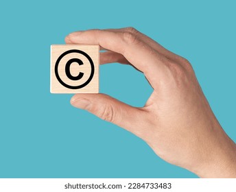 World book and copyright day. Hand with C for intellectual property protection sign in circle on cube. High quality photo