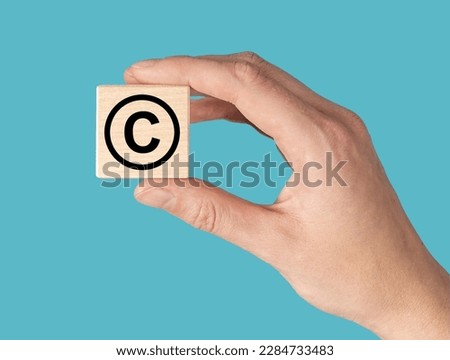 World book and copyright day. Hand with C for intellectual property protection sign in circle on cube. High quality photo