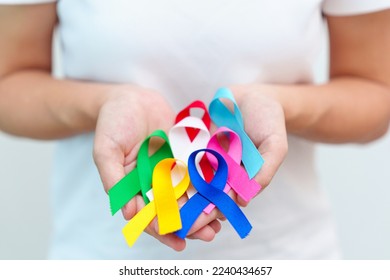 World cancer day, February 4. Hand holding blue, red, green, white, pink, navy blue and yellow ribbons for supporting people living and illness. Healthcare and Autism awareness day concept - Powered by Shutterstock