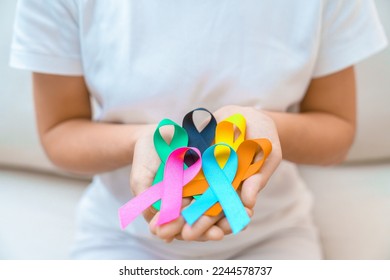 World cancer day, February 4. Hand holding blue, orange, teal, pink, black and yellow ribbons for supporting people living and illness. Healthcare and Autism awareness day concept