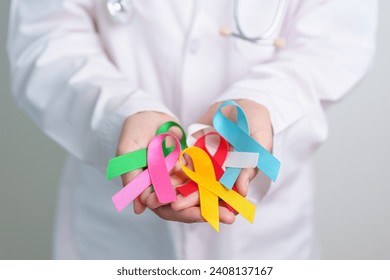 World cancer day, February 4. Doctor holding blue, red, green, white, pink, blue and yellow ribbons for supporting people living and illness. Healthcare and Autism awareness day concept - Powered by Shutterstock