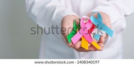 World cancer day, February 4. Doctor holding blue, red, green, white, pink, blue and yellow ribbons for supporting people living and illness. Healthcare and Autism awareness day concept