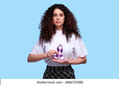 World Cancer Day. Woman Holding Purple Ribbon Symbol Of Fight Cancer Day. Isolated Blue Background