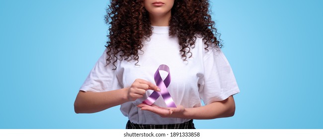 World Cancer Day. Woman Holding Purple Ribbon Symbol Of Fight Cancer Day. Isolated Blue Background