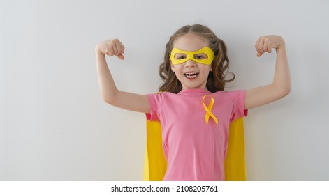 World Childhood cancer Day.  Girl in superhero costume with golden ribbon. 