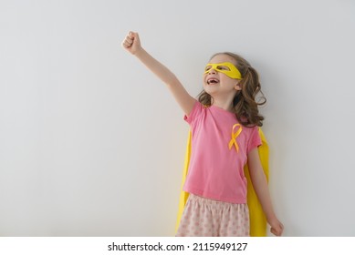 World Childhood cancer Day.  Girl in superhero costume with golden ribbon.  - Shutterstock ID 2115949127
