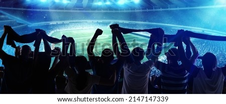 At world cup. Back view of football, soccer fans cheering their team with state flags and scarfs at crowded stadium at evening time. Concept of sport, cup, world, team, event, competition