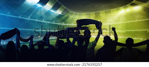 At world cup. Back view of football, soccer fans\
cheering their team with and scarfs at crowded stadium at evening\
time. Concept of sport, cup, world, team, event, competition. Blue,\
green, yellow