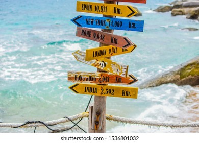 World direction signpost with distance to many different countries in the beach.