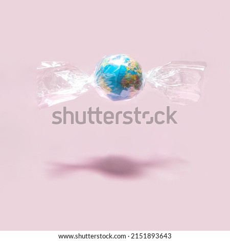 World Earth day concept. Globe in foil on pastel light pink background. Minimalistic environment composition. Creative candy world composition. Beauty of the planet idea.