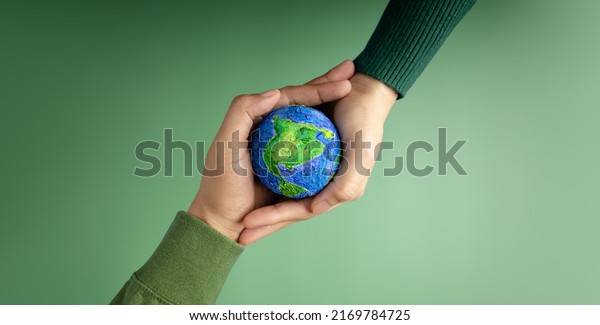 World Earth Day Concept. Green Energy, ESG,\
Renewable and Sustainable Resources. Environmental Care. Hands of\
People  Embracing a Handmade Globe. Protecting Planet Together. Top\
View