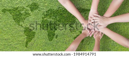 World environment day with global community teamwork, CSR and ESG environmental energy saving collaboration of young children hands stack together on green background for sustainable development goal