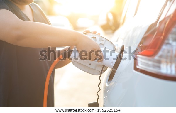 World Environment Day. save world\
save life concept. Close up woman hand holding electric car plug\
for recharge plug in hybrid car at home or charging\
station.