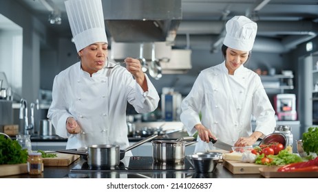 World Famous Restaurant: Duo Team of Asian and Black Female Chefs Cooking Delicious and Authentic Food, Perfect Teamwork in Preparing Healthy Meal in Modern Kitchen. Fusion Cuisine Masters. Wide Shot - Powered by Shutterstock