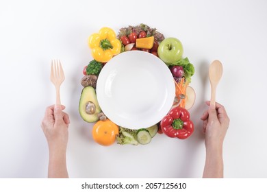 World Food Day, Vegetarian Day, Vegan Day Concept. Top View Of Woman Hand Holding Fork And Spoon With Fresh Vegetables, Fruit On White Paper Background.