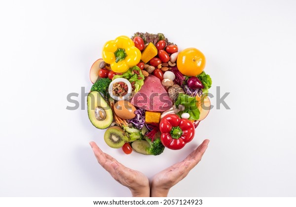World food day, vegetarian day, Vegan day\
concept. Top view of woman hand covering fresh vegetables, fruit on\
white paper background.