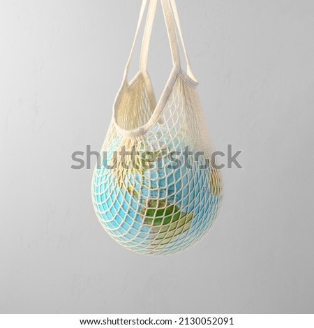 World globe in crochet bag, floating in air on light gray background. Eco-friendly life in the style of zero waste. Earth day, save the planet.