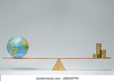 World Globe And Money Coins Stack Balancing On A Seesaw