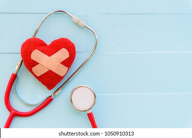 World Health Day, Healthcare And Medical Concept. Woman Hand Holding Red Heart With Stethoscope, Notepad, Thermometer And Yellow Pill On Pastel White And Blue Wooden Table Background Texture.