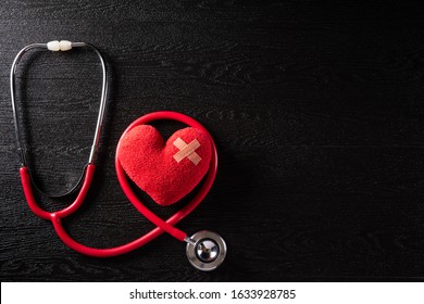 World Health Day, Healthcare And Medical Concept. Red Heart With Stethoscope On Black Wooden Table Background Texture.