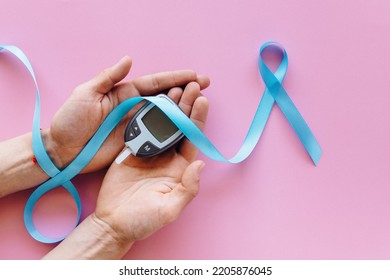 World Heart Day - Glucose Meter In Hand And Blue Ribbon 