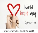 World heart day September 29 poster. A hand holding a red heart and text on a white background