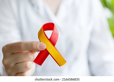 World hepatitis day. Doctor woman holding in her hands red yellow ribbon. Awareness of prevention and treatment viral hepatitis. Liver cancer. World cancer day. banner. close-up