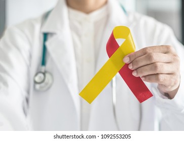 World hepatitis day and HIV/ HCV co-infection awareness with red yellow ribbon in medical doctor's hand symbolic bow color to support patient with illness and hepatic disease