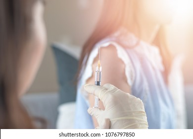 World immunization week and International HPV awareness day concept. Woman having vaccination for influenza or flu shot or HPV prevention  with syringe by nurse or medical officer. - Shutterstock ID 1076797850