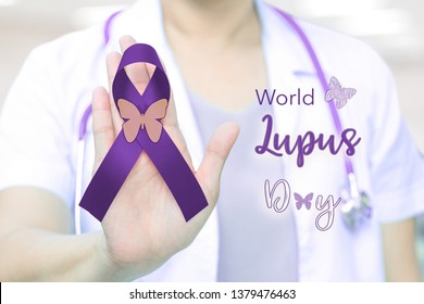 World Lupus Day With Purple Awareness Ribbon On Doctor Hand For Systemic Lupus Erythematosus (SLE) Campaine.