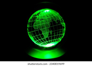 World map model engraved with a laser inside a glass globe. World map with green neon light on isolated black background. Asian and African continents are in the foreground. Clean world concept.