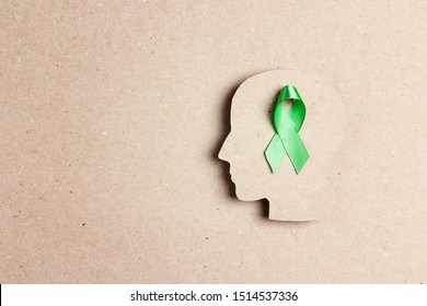 World Mental Health Day Concept. Green Awareness Ribbon With Brain Symbol On A Brown Background. Copy Space For Text.