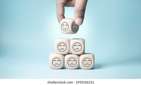 world mental health day concept or feedback rating and positive customer review, Businessman hand choose and turn sad face to smile face, wood cube stacking with sadness face icon on blue background - Powered by Shutterstock