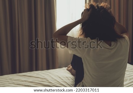 World Mental Health Day concept. Rear view of angry woman put hand on head and pulling hair. Mental illness woman sit on bed in bedroom. Woman with mental health problems. Stressed and nervous person.