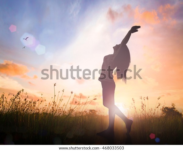 health concept: Silhouette of healthy woman raised hands for praise and worship God at autumn sunset meadow background, hospital mural wallpaper. 