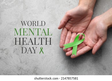 World Mental Health Day. Woman holding green ribbon at grey table, top view - Shutterstock ID 2147857581