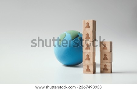 World population concept with gray background for copying text. Earth and human symbols on stacked wooden blocks.
