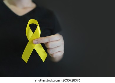 World Suicide Prevention Day. Human Hands Holding Yellow Ribbon Awareness Symbol For Preventing Suicide On Black Background. Mental Health Care Concept.