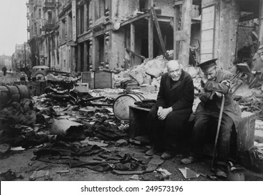 World War 2, Battle of Berlin, May 1945. Two elderly German men, one wearing the armband signifying blindness, the other his helper, sitting on a crate amid the rubble. Photo by Yevgeny Khaldei.