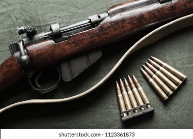World war era rifle and ammunition on military green fabric. Top down view.